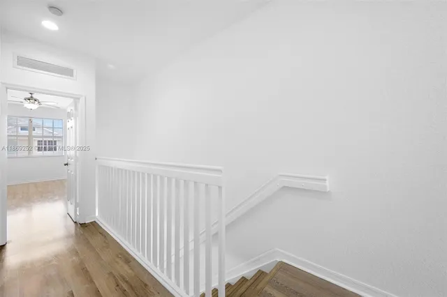 a view of a hallway with wooden floor and a bathroom