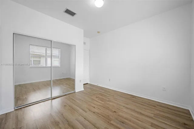 an empty room with wooden floor and window