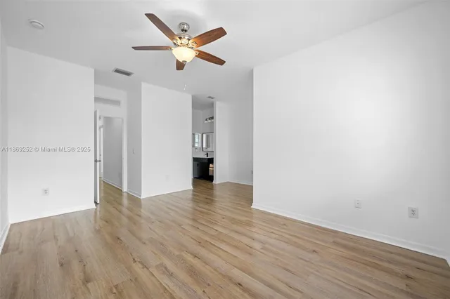 an empty room with wooden floor and a ceiling fan