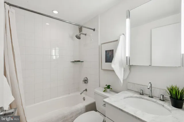 a bathroom with a granite countertop sink a toilet and shower