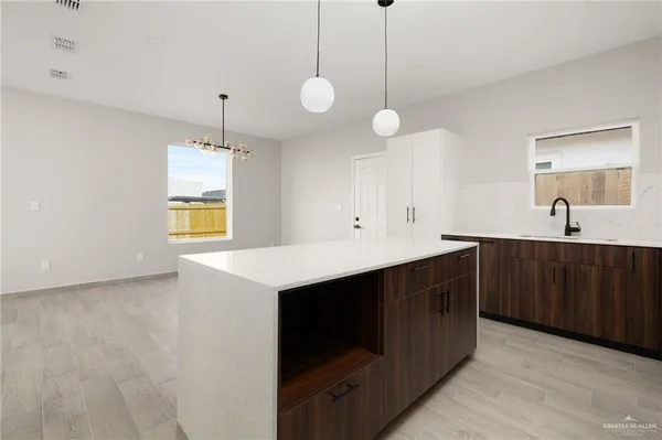 a kitchen with a sink a chandelier and cabinets