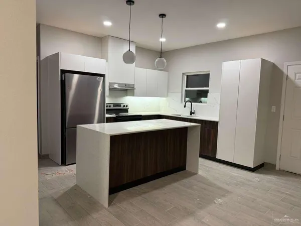 a kitchen with stainless steel appliances granite countertop a refrigerator a sink a oven and a oven with wooden floor