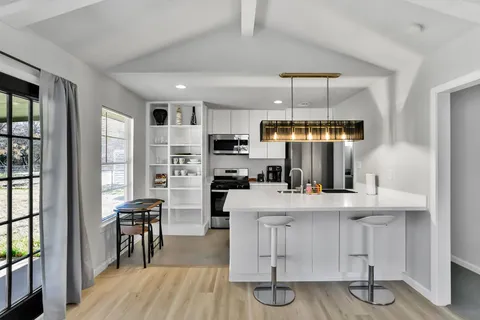 a kitchen with stainless steel appliances a dining table chairs and wooden floor