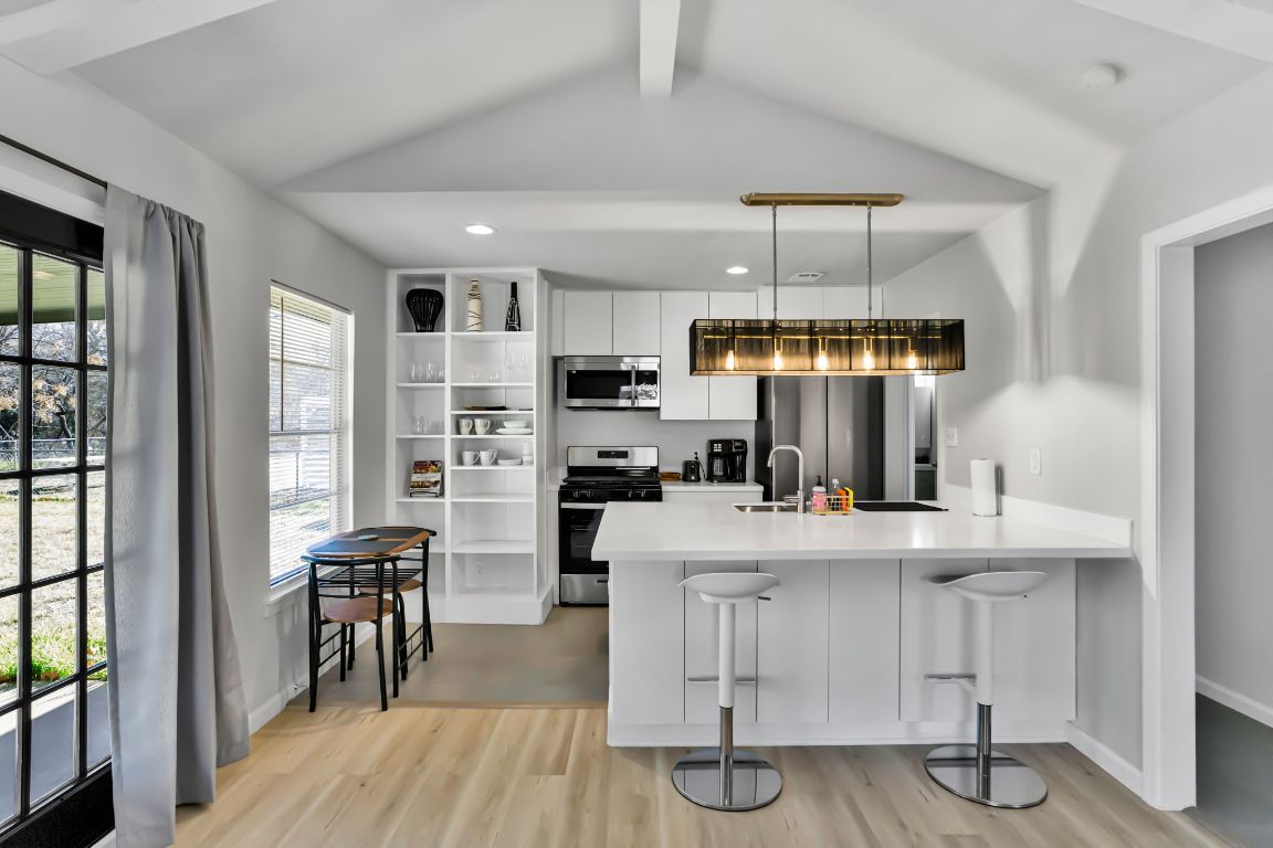 1205 Arthur Stiles Road Austin, TX 78721 - Photo 7 of 20 a kitchen with stainless steel appliances a dining table chairs and wooden floor