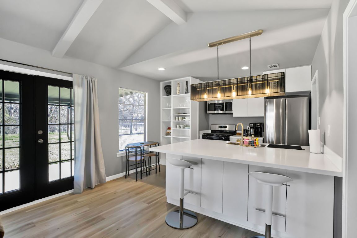 1205 Arthur Stiles Road Austin, TX 78721 - Photo 8 of 20 a kitchen with kitchen island granite countertop a stove a sink a refrigerator and white cabinets with wooden floor