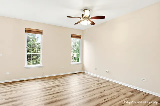 an empty room with wooden floor fan and windows