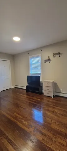 a view of an empty room with wooden floor and a fireplace