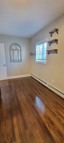 an empty room with wooden floor and window