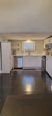 a view of kitchen and empty room with wooden floor
