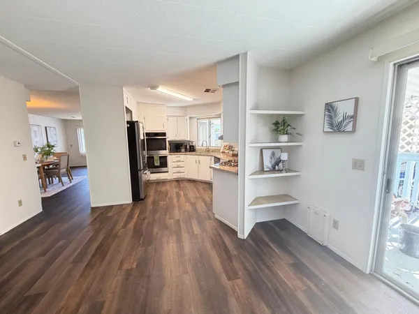 a living room with stainless steel appliances furniture cabinets and wooden floor