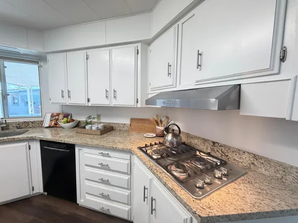 a kitchen with granite countertop white cabinets and a stove