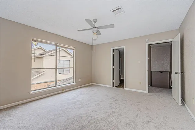 an empty room with windows and ceiling fan