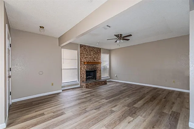 an empty room with wooden floor and a ceiling fan