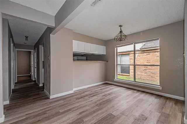 an empty room with wooden floor cabinet and windows