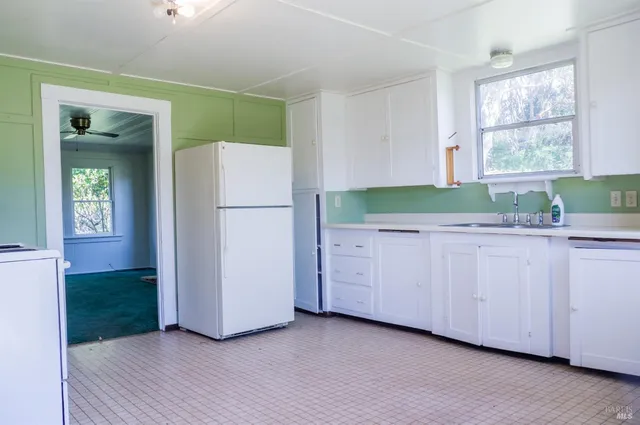 a kitchen with white cabinets and a refrigerator