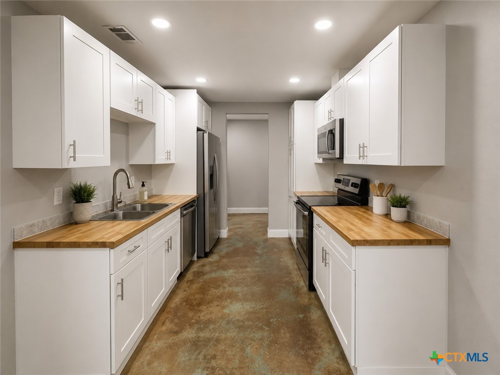 661 West Austin Street, Unit Q Luling, TX 78648 - Photo 3 of 9 a large kitchen with stainless steel appliances granite countertop a sink and a stove top oven
