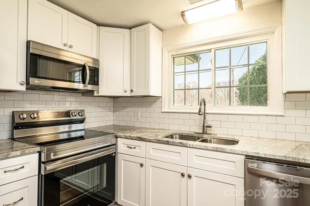a kitchen with stainless steel appliances granite countertop white cabinets granite counter tops and a window