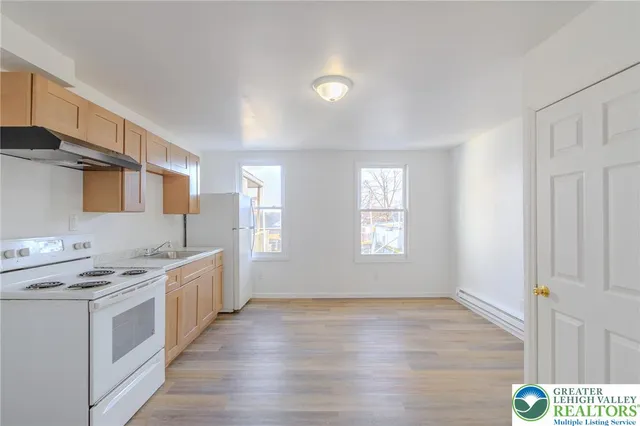 a kitchen with stainless steel appliances a stove top oven a sink dishwasher and a refrigerator with wooden floor