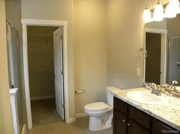 a bathroom with a granite countertop sink and a toilet