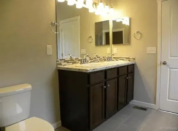a bathroom with a granite countertop sink toilet and mirror