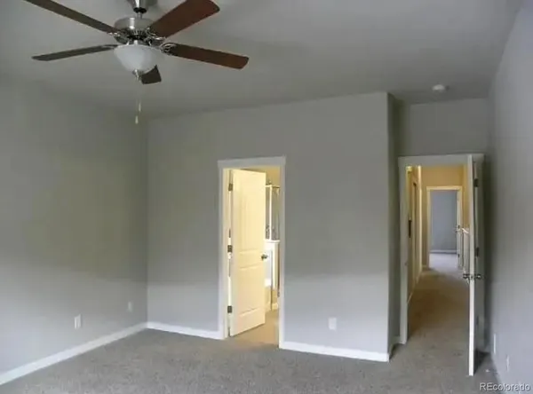 an empty room with a ceiling fan and a carpet
