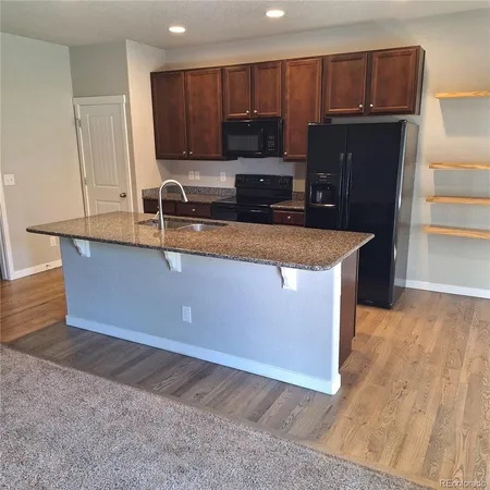 a kitchen with stainless steel appliances granite countertop a sink a stove a refrigerator a microwave and with wooden cabinets