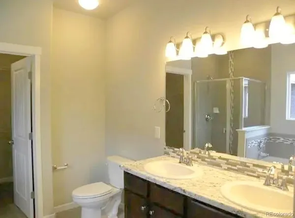 a bathroom with a granite countertop sink vanity mirror and toilet