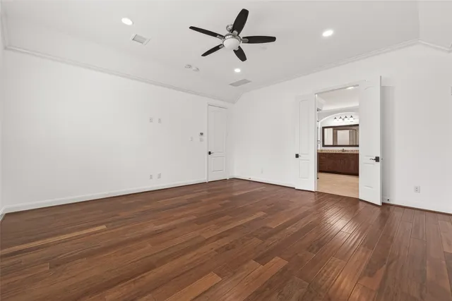 an empty room with wooden floor and ceiling fan