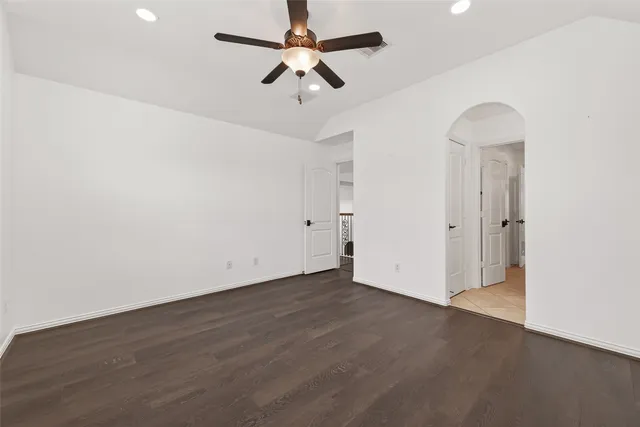 an empty room with wooden floor ceiling fan and window