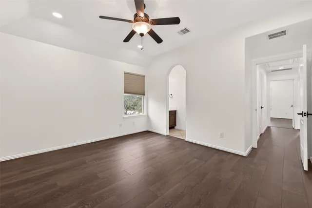 an empty room with wooden floor ceiling fan and windows