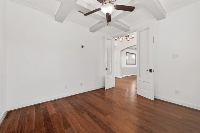 an empty room with wooden floor ceiling fan and windows