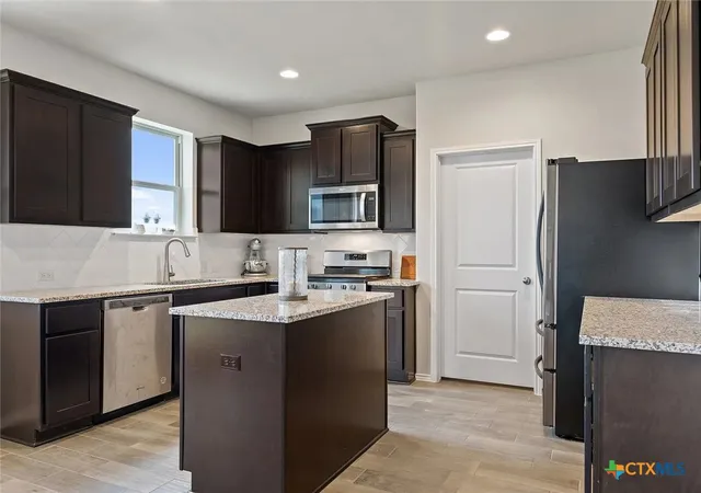 a kitchen with stainless steel appliances granite countertop a sink stove and refrigerator