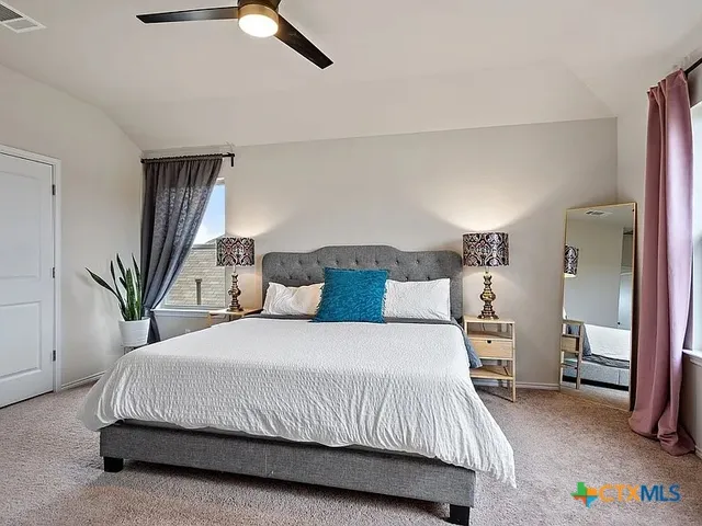 a bedroom with a bed and a potted plant on the dresser