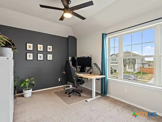a view of a workspace with furniture and a window