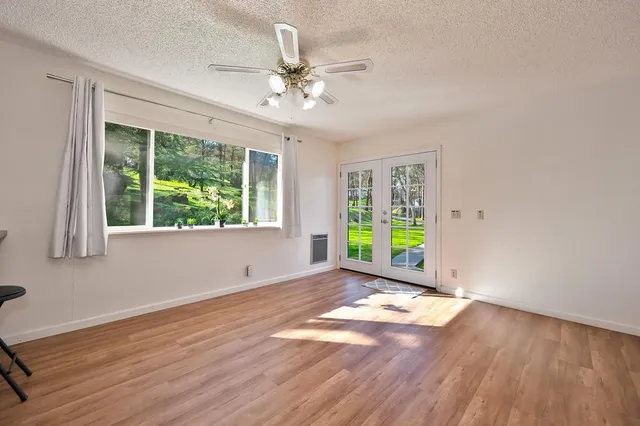 a view of an empty room with wooden floor and a window
