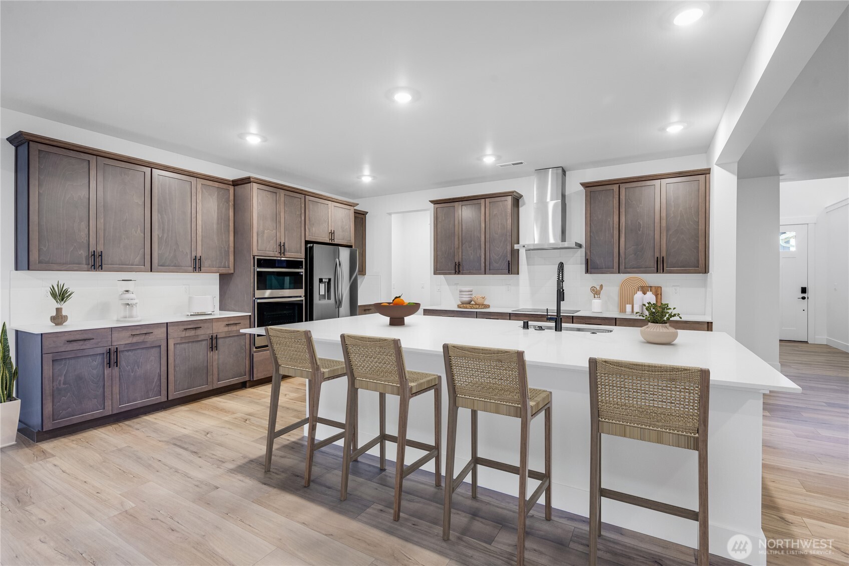 6034 Trce Drive Southwest Port Orchard, WA 98367 - Photo 2 of 40 a kitchen with kitchen island granite countertop wooden floors and white cabinets
