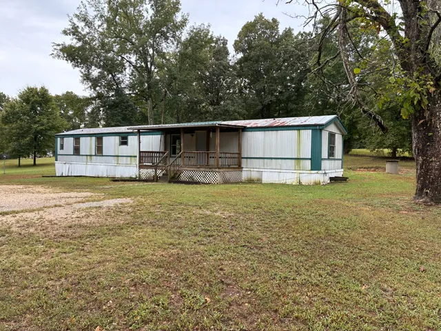 a front view of house with yard and trees in the background