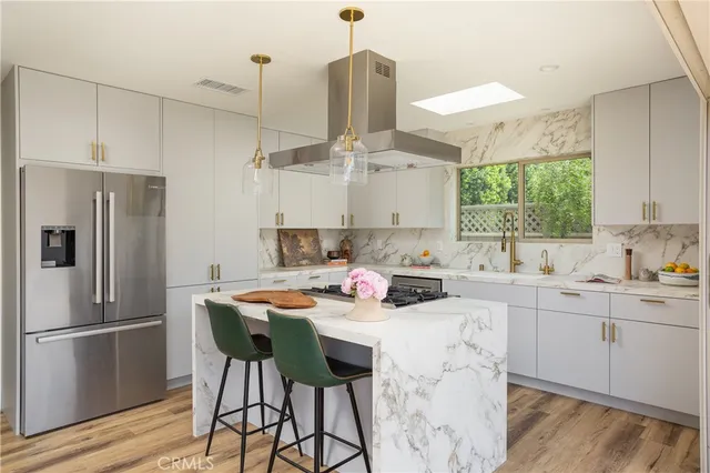 a kitchen with stainless steel appliances kitchen island a table chairs refrigerator and sink