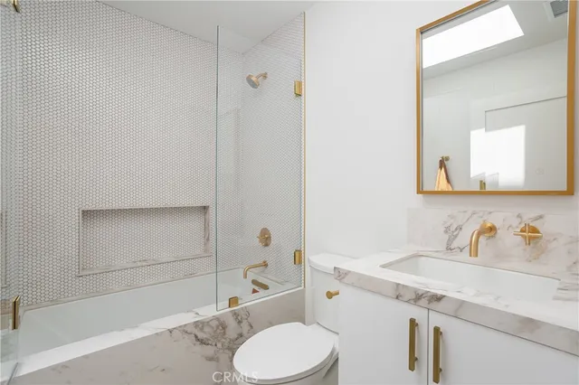 a bathroom with a granite countertop sink toilet and mirror