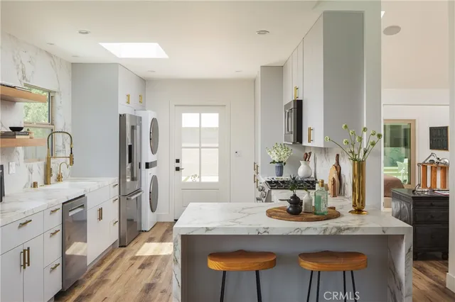 a kitchen with stainless steel appliances kitchen island granite countertop a table chairs in it and wooden floors