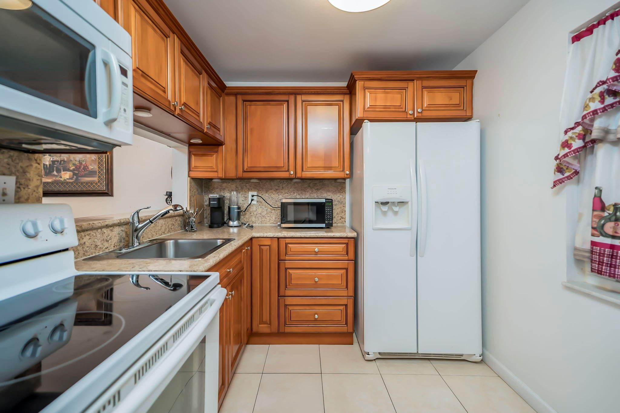 9401 Lime Bay Boulevard, Unit 209 Tamarac, FL 33321 - Photo 8 of 24 a kitchen with stainless steel appliances granite countertop a refrigerator stove and sink
