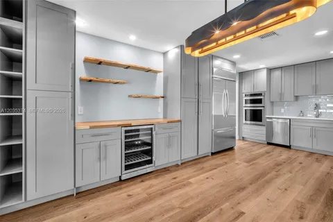 a kitchen with a refrigerator stainless steel appliances wooden floor and cabinets