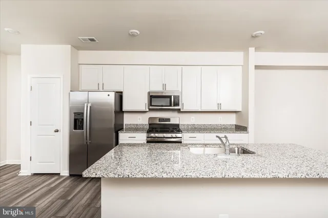 a kitchen with stainless steel appliances granite countertop a sink a refrigerator and a granite counter tops