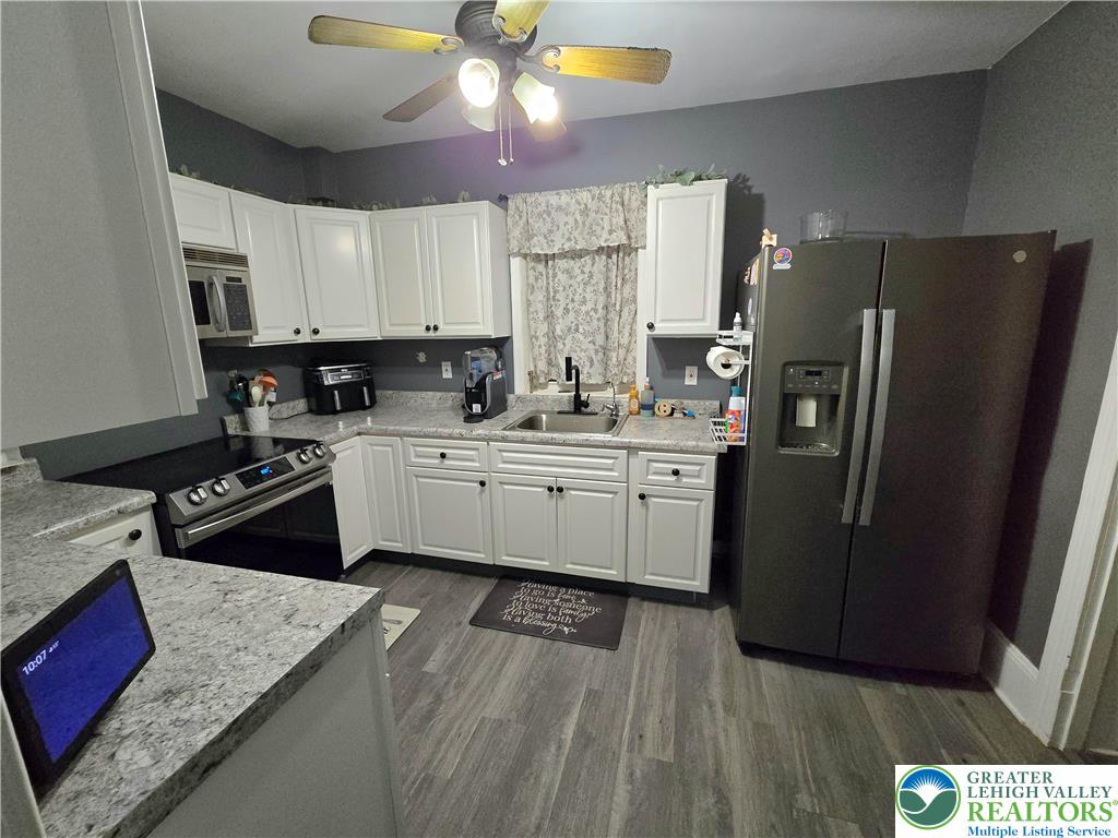 129 Rattlesnake Hill Road Boyertown, PA 19512 - Photo 14 of 26 a kitchen with a sink dishwasher a refrigerator a stove and white cabinets with wooden floor