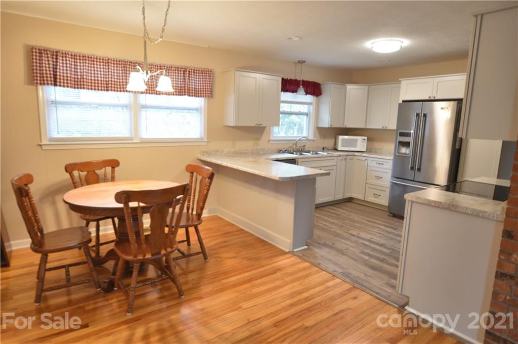200 Bradshaw Road Tryon, NC 28782 - Photo 4 of 24 a kitchen with a table chairs refrigerator and wooden cabinets
