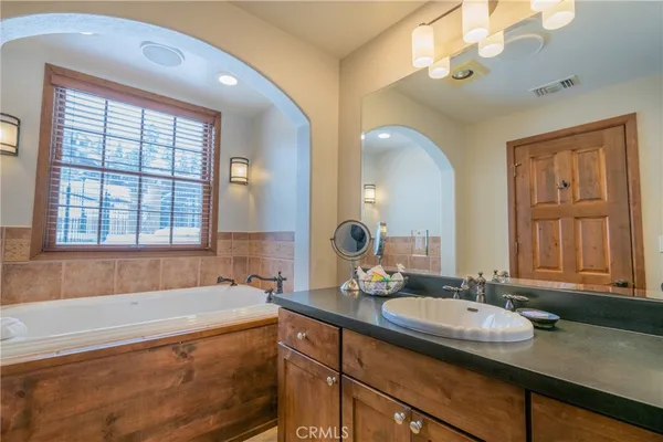 a bathroom with a granite countertop tub sink and mirror