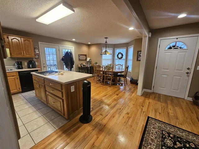 a kitchen with stainless steel appliances granite countertop a stove top oven a sink a dining table and chairs with wooden floor