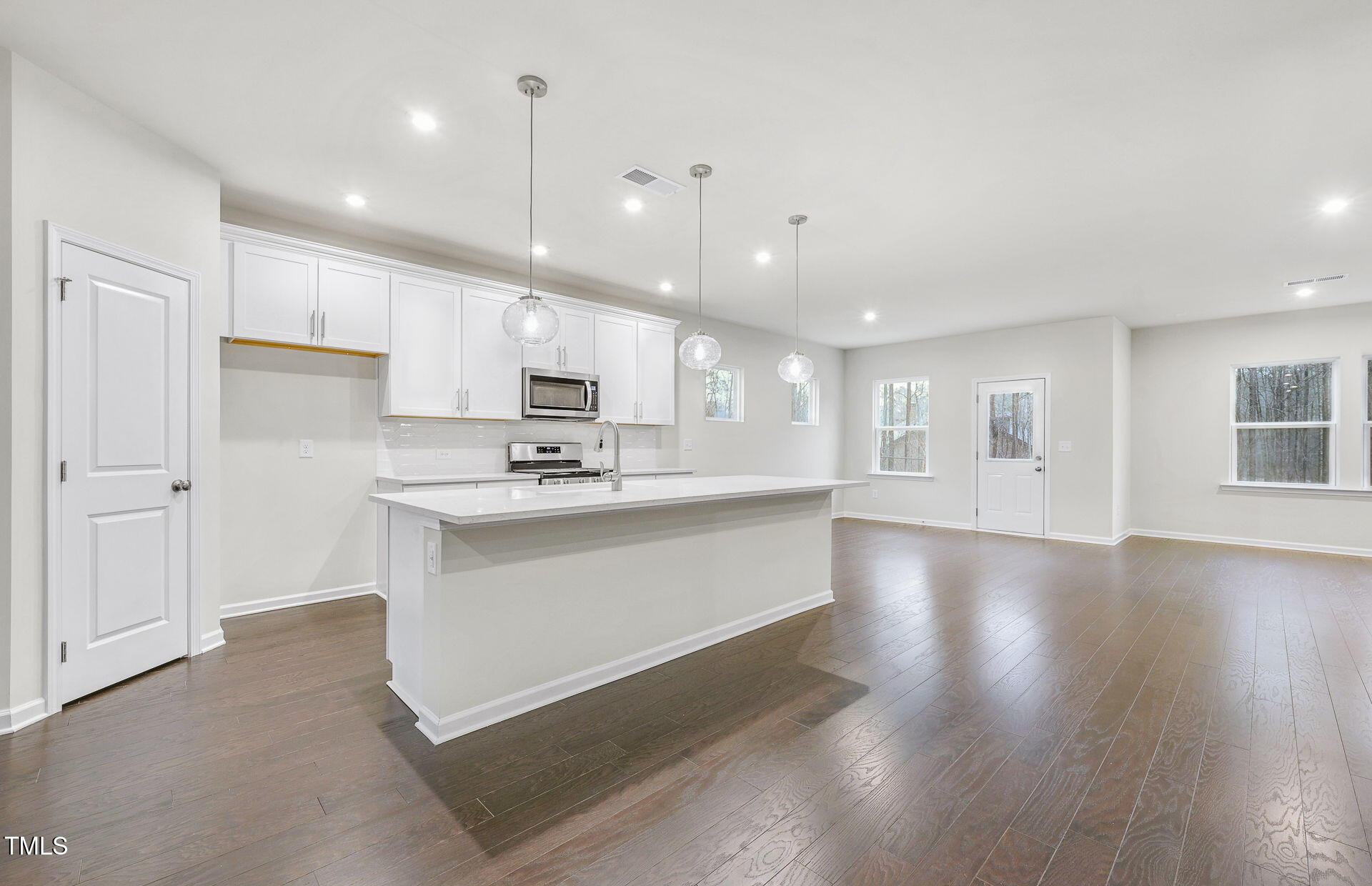 1103 Freestone Road Durham, NC 27703 - Photo 3 of 17 a large white kitchen with kitchen island a sink a center island stainless steel appliances and a fireplace