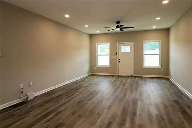 an empty room with wooden floor and windows