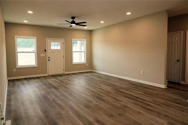 an empty room with wooden floor and windows